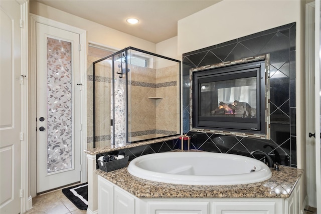 bathroom featuring tile patterned floors, a garden tub, a shower stall, and a tile fireplace