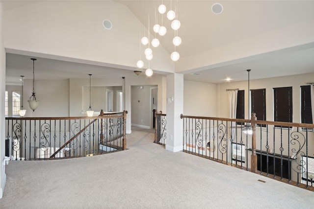 carpeted spare room featuring baseboards, high vaulted ceiling, and an inviting chandelier