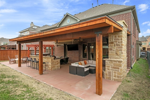 view of patio with outdoor dry bar, an outdoor kitchen, a fenced backyard, outdoor lounge area, and ceiling fan