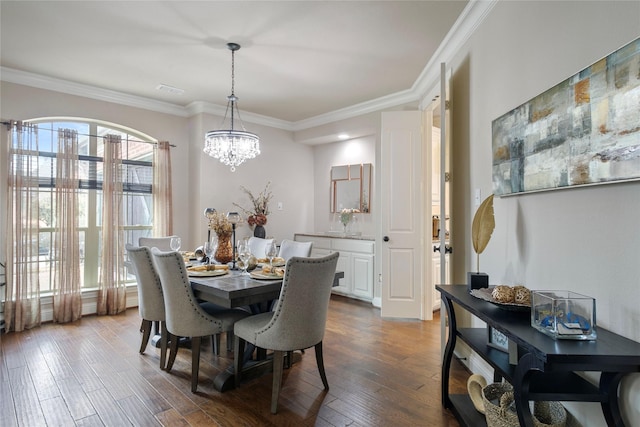 dining room featuring visible vents, a notable chandelier, wood finished floors, and crown molding