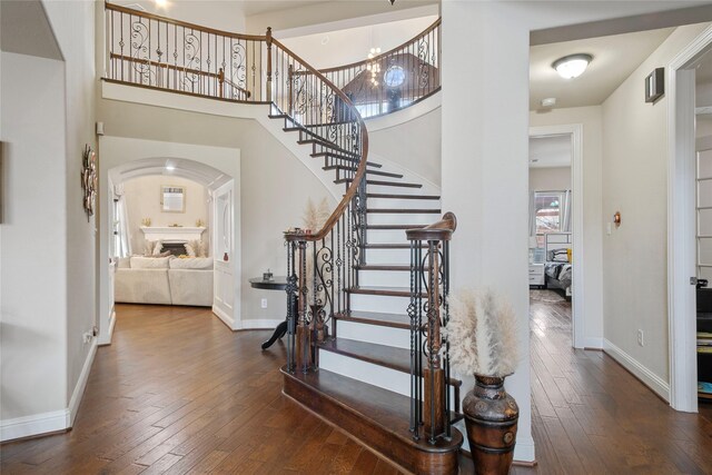 staircase with a fireplace, baseboards, and hardwood / wood-style flooring