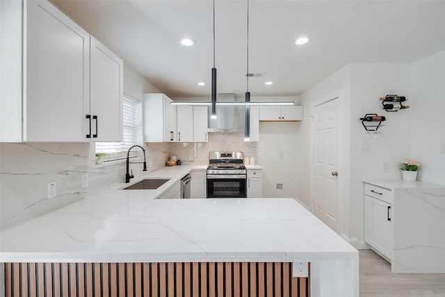 kitchen with light stone counters, visible vents, a peninsula, a sink, and stainless steel appliances