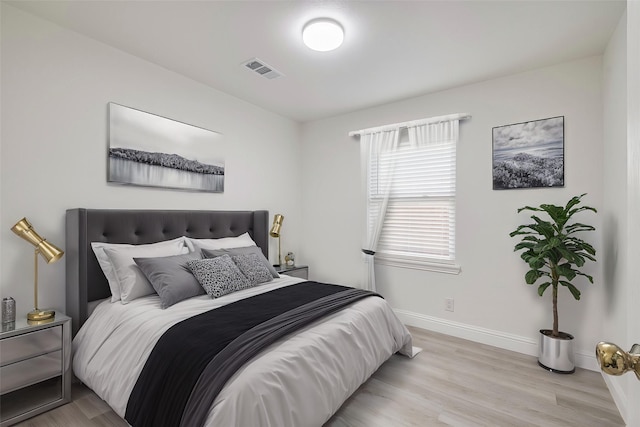 bedroom with visible vents, baseboards, and light wood finished floors