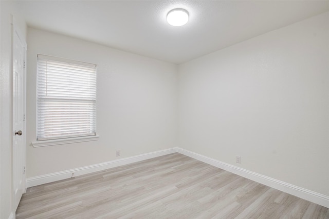 spare room with baseboards and light wood-type flooring