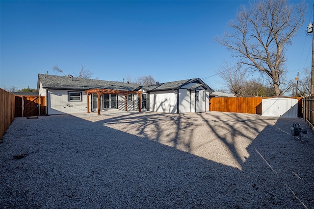 rear view of house featuring an outdoor structure, a gate, a fenced backyard, and a shed