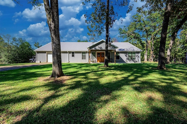 view of front facade featuring a standing seam roof, board and batten siding, a front yard, an attached garage, and metal roof