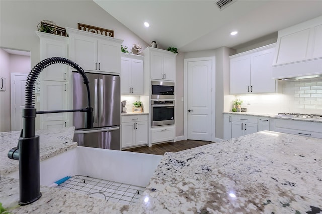 kitchen featuring visible vents, lofted ceiling, white cabinets, appliances with stainless steel finishes, and tasteful backsplash