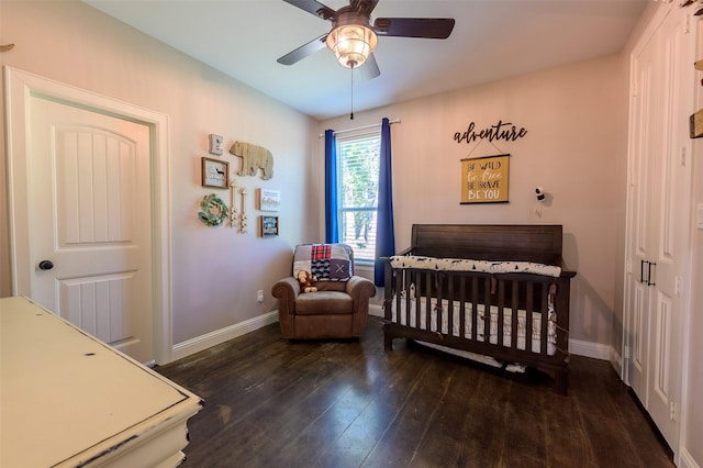 bedroom with ceiling fan, baseboards, a nursery area, and wood finished floors