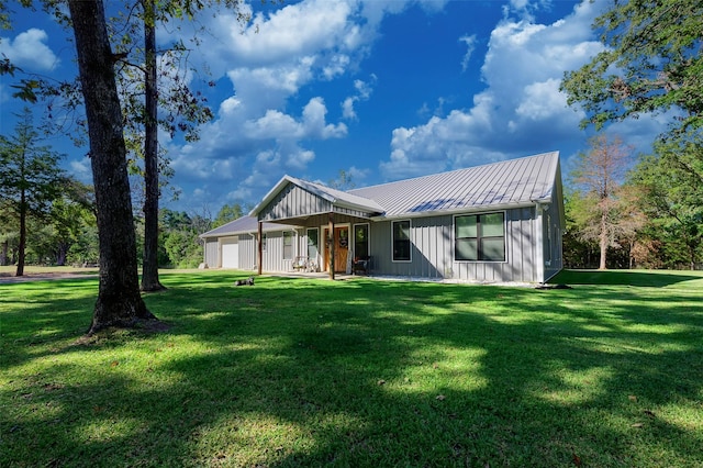 rear view of house with a standing seam roof, a yard, board and batten siding, metal roof, and a garage