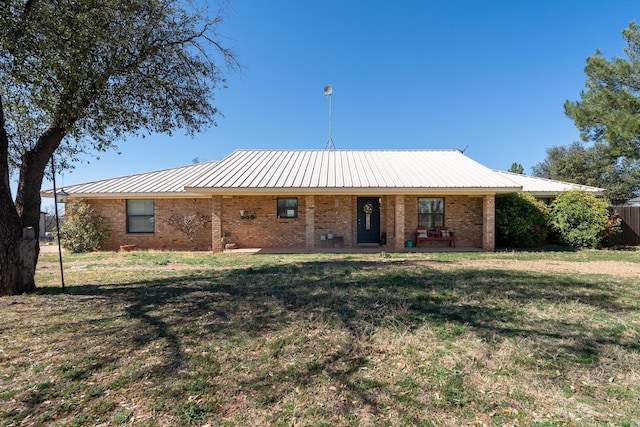 single story home with a front yard, brick siding, and metal roof