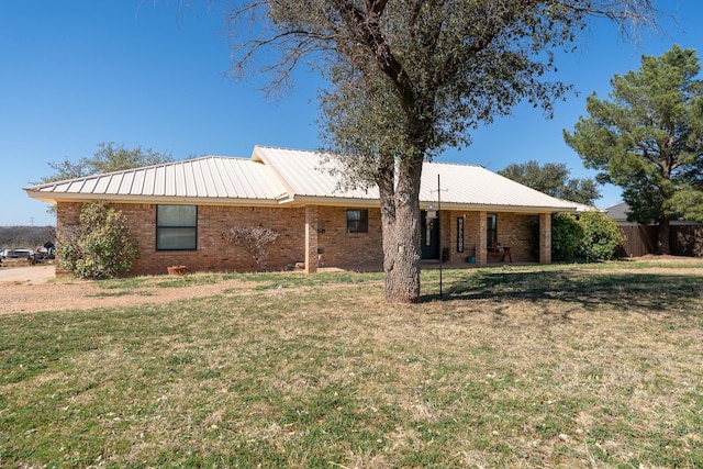 view of front facade with brick siding, metal roof, a front yard, and fence