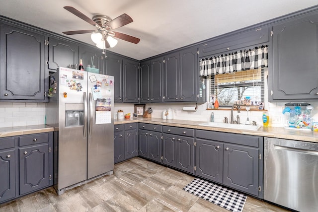 kitchen featuring decorative backsplash, appliances with stainless steel finishes, light countertops, and a sink