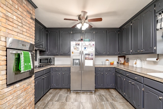 kitchen with light countertops, brick wall, tasteful backsplash, and appliances with stainless steel finishes