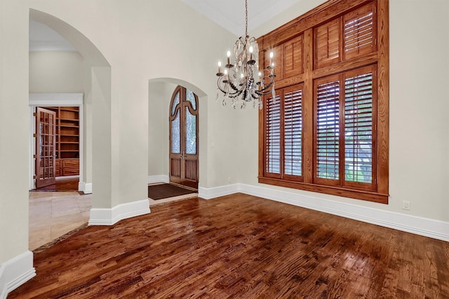 empty room with arched walkways, plenty of natural light, and wood finished floors