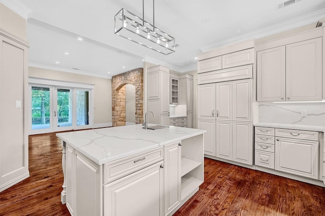 kitchen featuring arched walkways, white cabinetry, and crown molding