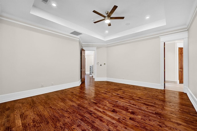 spare room with visible vents, wood finished floors, baseboards, crown molding, and a raised ceiling