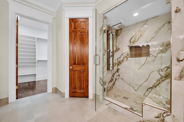 bathroom with a marble finish shower, baseboards, and ornamental molding