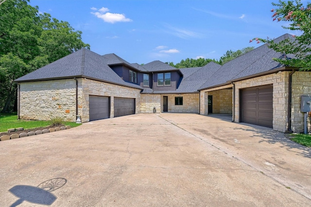 view of front of home featuring a garage, driveway, and roof with shingles