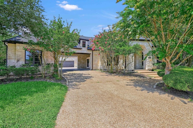 view of property hidden behind natural elements featuring stone siding, concrete driveway, and a garage