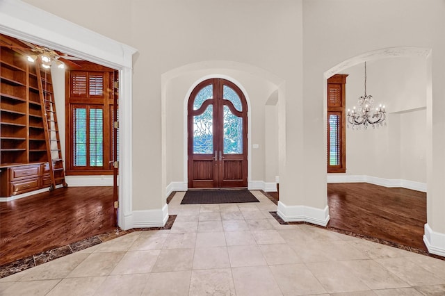 tiled foyer featuring arched walkways, plenty of natural light, and baseboards