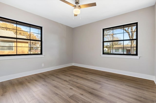 unfurnished room featuring a ceiling fan, a wealth of natural light, baseboards, and wood finished floors