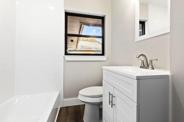 bathroom featuring vanity, toilet, baseboards, washtub / shower combination, and wood finished floors