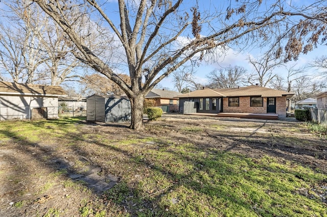 view of front of property with brick siding, an outbuilding, fence, and a storage shed