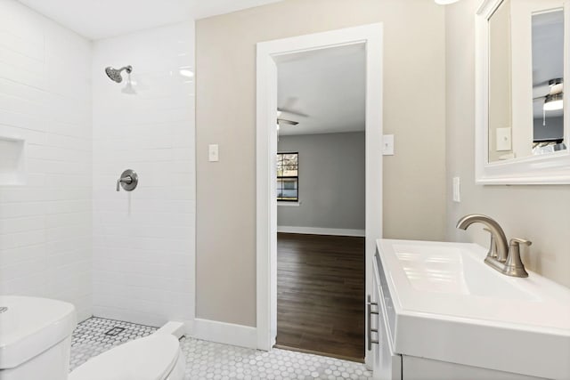 full bathroom with tile patterned floors, tiled shower, toilet, and baseboards