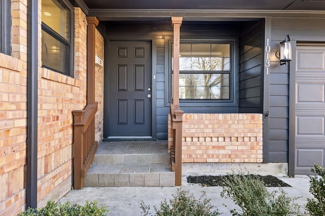 view of exterior entry featuring brick siding, a porch, and an attached garage