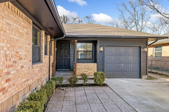 entrance to property featuring brick siding, concrete driveway, a garage, and roof with shingles