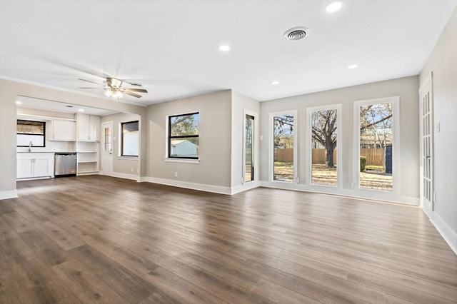 unfurnished living room with visible vents, a sink, dark wood finished floors, recessed lighting, and baseboards