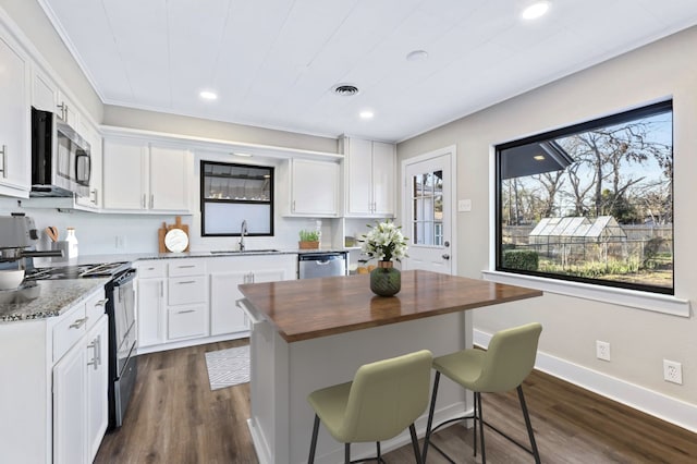 kitchen featuring visible vents, stainless steel appliances, butcher block counters, white cabinetry, and a sink