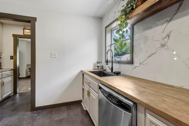 kitchen with stainless steel dishwasher, butcher block countertops, baseboards, and a sink