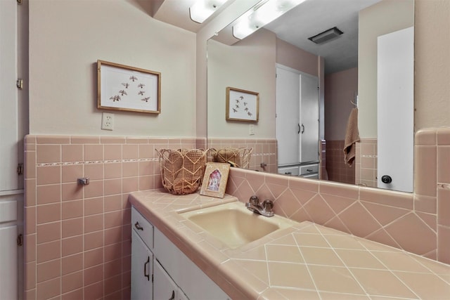 bathroom with a wainscoted wall, tile walls, and vanity