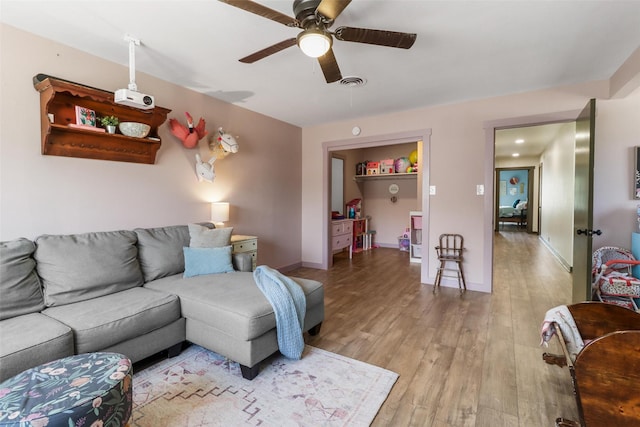 living room featuring light wood-style flooring, baseboards, visible vents, and ceiling fan