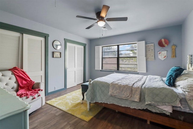 bedroom featuring baseboards, two closets, ceiling fan, and wood finished floors