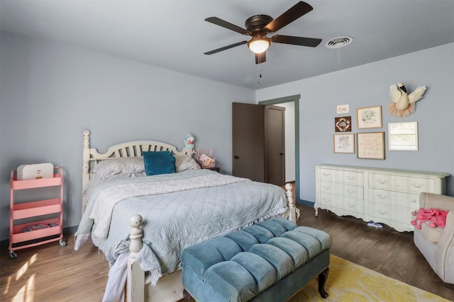 bedroom featuring a ceiling fan, wood finished floors, visible vents, and baseboards