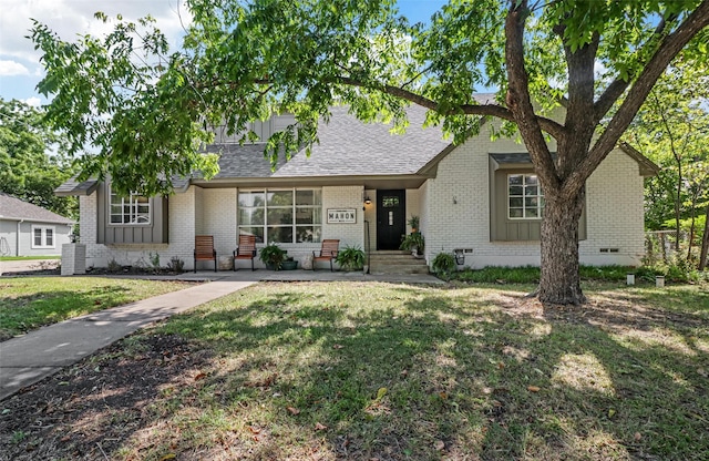 view of front of home featuring a shingled roof, a front lawn, brick siding, and crawl space