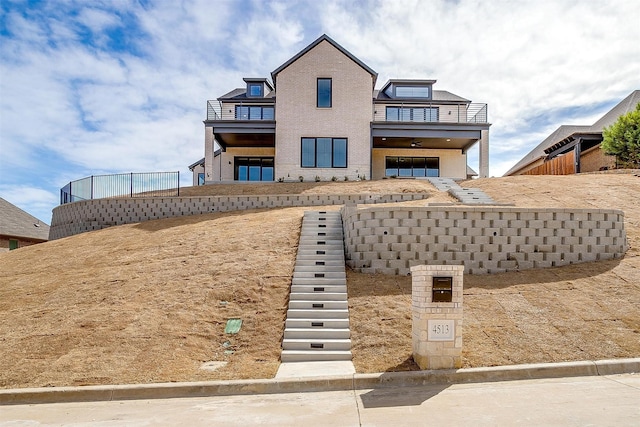 view of front of house with stairway, a balcony, and fence