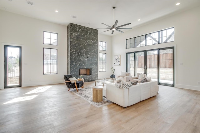 living room featuring plenty of natural light, light wood-style floors, french doors, and a premium fireplace