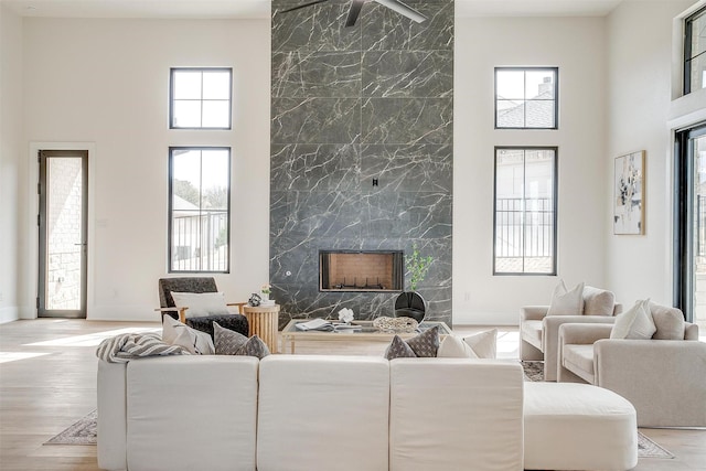 living room featuring a towering ceiling, baseboards, wood finished floors, and a fireplace