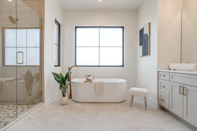 bathroom with a shower stall, vanity, baseboards, and a freestanding tub