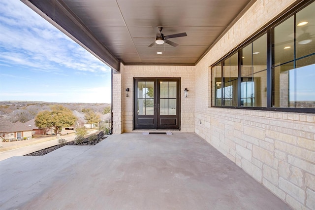 view of exterior entry with brick siding, french doors, and a ceiling fan