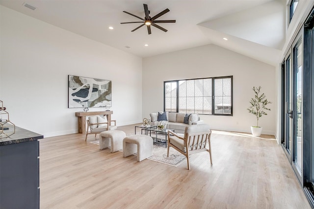 living room featuring a ceiling fan, baseboards, visible vents, light wood finished floors, and high vaulted ceiling