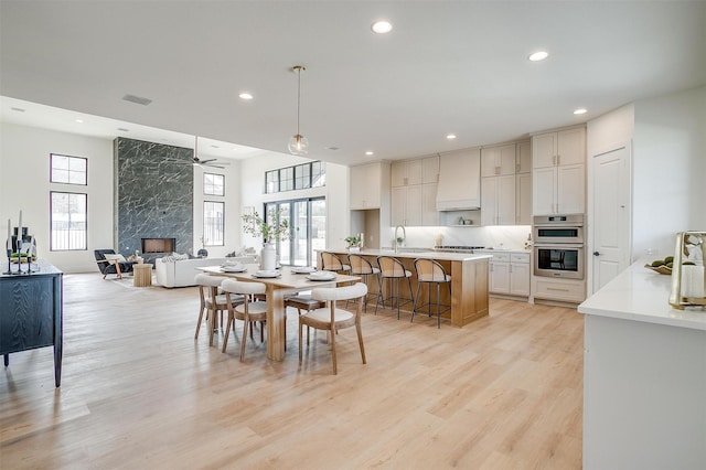 dining room with recessed lighting, plenty of natural light, light wood-style floors, and a fireplace