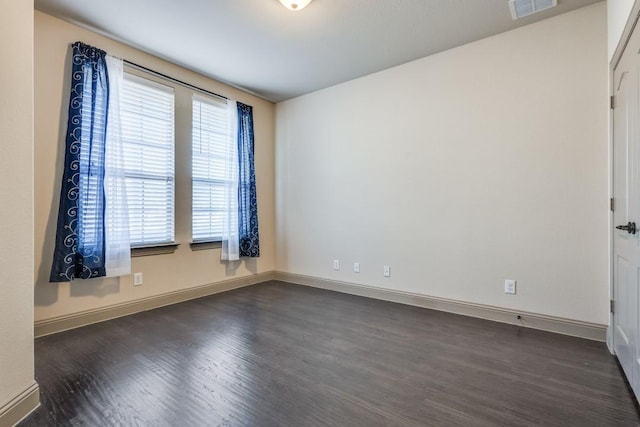 spare room featuring dark wood finished floors, baseboards, and visible vents