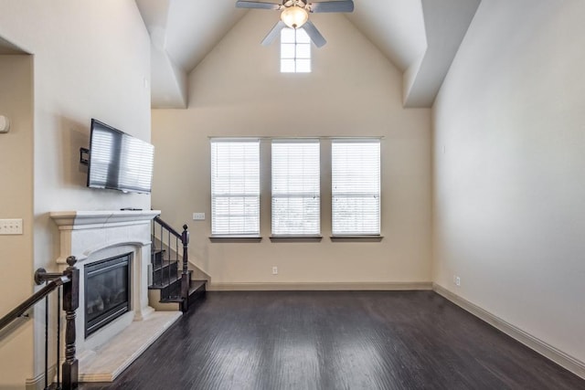 unfurnished living room with a ceiling fan, a glass covered fireplace, wood finished floors, stairway, and baseboards