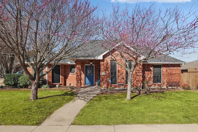 ranch-style house featuring brick siding, a front lawn, and fence