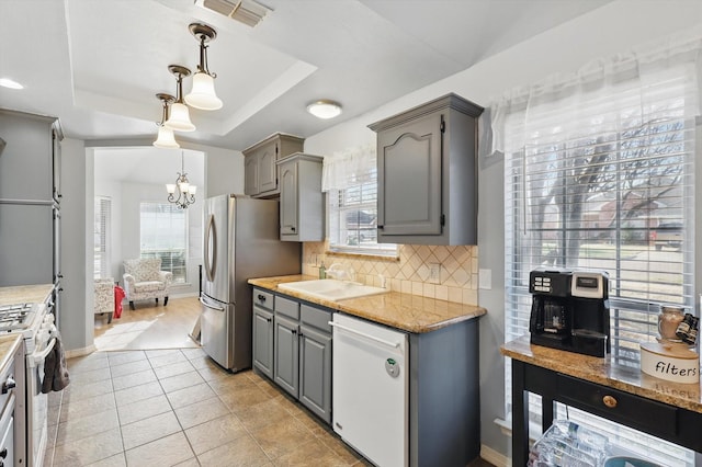 kitchen with white appliances, visible vents, gray cabinets, a sink, and a raised ceiling