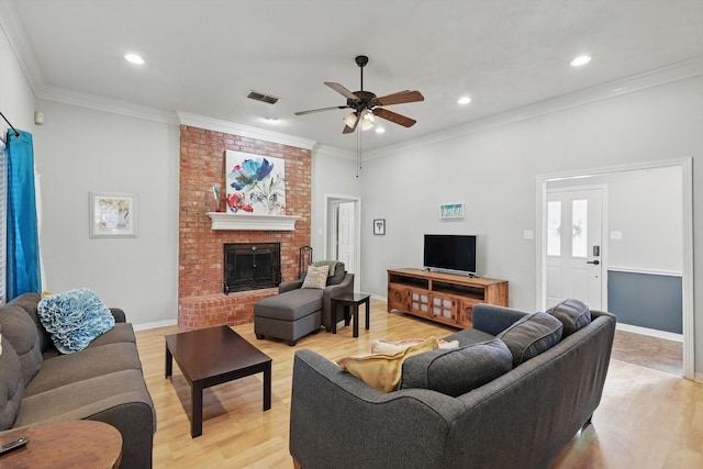 living room featuring visible vents, ornamental molding, recessed lighting, a fireplace, and light wood finished floors